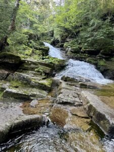 A serene waterfall cascading through a forested area in Waterville Valley, New Hampshire.