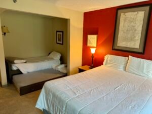 Hotel room at Golden Eagle Lodge featuring a queen bed and a trundle bed, with ski-themed decor