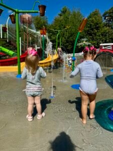 Two toddlers enjoying the water park at Story Land, splashing in the fountains.