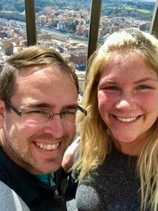 Couple at the top of St. Peter’s Basilica with a panoramic view of Rome in the background.