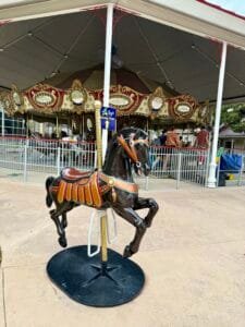 A stationary horse outside the accessible carousel at Morgan's Wonderland, allowing children to try sitting on it before riding.