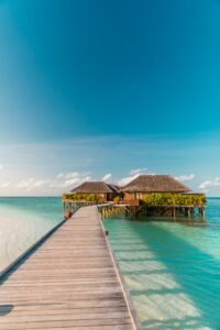 A wooden boardwalk stretching over turquoise waters, leading to luxurious overwater bungalows in the Maldives.